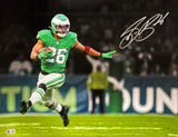 Saquon Barkley, in a green Eagles uniform, runs with the football and extends his left arm in this 16x20 photo. The piece from Sports Integrity features his bold autograph in the upper right and blurred stadium details in the background.