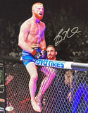 The Sports Integrity Bo Nickal Signed 11x14 UFC Photo JSA ITP features Bo Nickal, red-bearded in blue shorts, celebrating atop the octagon cage before a cheering arena crowd. The photo includes his visible autograph.