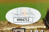 A close-up of a white oval sticker labeled “MH94712” with a faint Mariano Rivera signature on a framed 16x20 New York Yankees photo by Sports Integrity (For Life JSA), set against a blurred baseball field background.