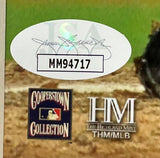 A close-up of a sticker with a signature and code MM94717 above Cooperstown Collection and Highland Mint/MLB logos, set against a blurred field on the Mariano Rivera Signed Framed 16x20 Yankees Photo by Sports Integrity.