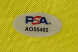 An official PSA hologram (code "AO55460") is placed on the Phil Mickelson Signed Framed Undated Masters Golf Flag by Sports Integrity, shown on a textured yellow surface.