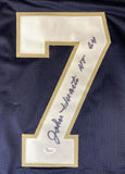 The Sports Integrity John Huarte Notre Dame Navy Blue Jersey features a large white and gold #7 signed "John Huarte HT 64" in black ink, plus a JSA hologram authentication sticker at the bottom of the number.