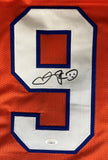 The Sports Integrity Adam Sandler "The Waterboy" Boucher football jersey features an orange design with a large white and blue number 9, a black signature in the center, and a JSA authentication sticker at the bottom.