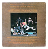 Back cover of Aerosmith Toys in the Attic 1975 Vinyl Record 4 by Sports Integrity features six people among colorful items and a white dog, with gold song titles and credits above on a textured brown background.