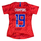 The Sports Integrity Alex Morgan Signed 2019/20 Nike USA Women's Champions Soccer Jersey features CHAMPIONS and #19 on the back, a signature, blue and white accents, plus several small logos near the bottom.