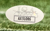 A Sports Integrity Amon-Ra St. Brown Signed Framed 8x10 Detroit Lions Photo features a white oval JSA certification sticker labeled AX51086 with a faint logo and signature on a green grassy background.