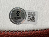 Close-up of a Beckett Witness Autograph authentication sticker and QR code (1W535199) on a Brian Dawkins Signed Philadelphia Eagles Logo Football by Sports Integrity, displayed on its white and brown surface with included case.