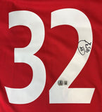 Carlos Tevez signed Manchester United red Adidas soccer jersey by Sports Integrity features white number 32 on the front, autographed in black marker with an inscription and a BAS QR code sticker for authenticity below the signature.