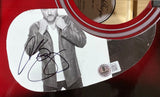 A close-up of the Sports Integrity Chris Young Signed 41" Losing Sleep Red Acoustic Guitar BAS shows a black-and-white image of a man in a jacket, Chris Young's autograph, a QR code sticker, and part of the glossy red guitar sound hole.