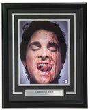 The Sports Integrity Christian Bale Signed Framed 11x14 American Psycho Photo (BAS) features Bale as Patrick Bateman, blood-splattered, eyes closed, tongue out, and includes a name plaque beneath the image.