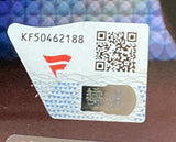 A close-up of a Sports Integrity sticker with code KF50462188, red logo, QR code, and holographic feature on the CM Punk Signed Framed 8x10 WWE Pipe Bomb Photo Fanatics, against a blurred background.