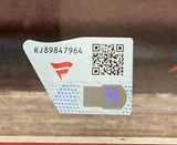 A close-up of a sticker with code RJ89847964, QR code, red abstract logo, and blue N on silver, attached to the Sports Integrity CM Punk Signed Framed 16x20 WWE Pipe Bomb Photo Fanatics.
