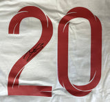 A white Dele Alli Signed England Soccer T-Shirt Jersey by Sports Integrity features a large red number 20 and a black autograph on the left side of the number 2.