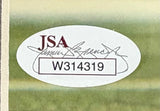 A Dez Bryant Signed Framed 8x10 Dallas Cowboys Photo by Sports Integrity features a JSA hologram with signature graphic and code W314319, placed on a green and beige surface.