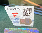 A close-up of a security label on the Dominik Mysterio Signed Framed 8x10 WWE Photo by Sports Integrity, showing code KF50462206, a red logo, a QR code, and a holographic element above another reflective security strip.