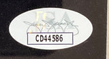 A Gene Hackman Signed Framed 8x10 Photo by Sports Integrity features a JSA oval sticker with a faint JSA in the background and bold code CD44586, affixed to the dark surface.