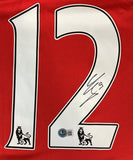 A close-up of the Olivier Giroud Signed Arsenal Nike Soccer Jersey by Sports Integrity, featuring a large white number 12 outlined in black, Premier League lion logo, signature, and certification sticker with QR code.