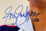 A close-up of a person in a blue, red, and white sports jacket features a large blue autograph and "USA" text—classic memorabilia: Jennie Finch Signed USA Softball 8x10 Photo with USA inscription by Sports Integrity.