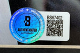 A close-up of the Beckett Authentication sticker featuring a blue holographic seal and QR code next to code BS67402 on a Joey Chestnut Signed Framed 8x10 Professional Eating Legend Photo Jaws Insc by Sports Integrity.