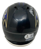 The Sports Integrity Johnathan Ogden Signed Baltimore Ravens Mini Speed Helmet features purple and gold team logos, a white chin strap, Ogden's silver autograph, and a Beckett authentication sticker on the back.