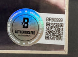 A Beckett Authenticated Autograph sticker with a holographic seal, QR code, and serial number BR90999 is attached to the corner of the Sports Integrity Jon Gries Signed Framed 8x10 Napoleon Dynamite Uncle Rico Photo w/ Quote BAS.