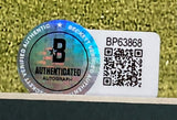 A Beckett Authenticated Autograph sticker (serial BP63868, large B logo, QR code, holographic seal) is affixed to a Justin Thomas Signed Framed 11x14 PGA Golf Photo by Sports Integrity, set against a green textured background.