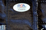 A close-up of a PSA In-The-Presence authentication sticker labeled 3C69415 on Kayla Harrison Signed Black UFC Venom Fight Trunks by Sports Integrity, attached to dark blue fabric with visible stitching.