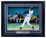 The Sports Integrity Ken Griffey Jr. Signed Framed 16x20 Seattle Mariners Photo (BAS ITP) features him in a white uniform swinging a bat, with his name on the plaque and fans visible in the background.