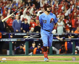 The Sports Integrity Kyle Schwarber Signed 16x20 Philadelphia Phillies Blue Jersey Photo (JSA) shows Schwarber in a blue Phillies uniform, flipping his bat after a hit, with crowd and World Series sign visible. Autograph included.