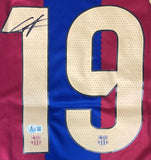A close-up of the Lamine Yamal Signed Barcelona Nike Long Sleeve Soccer Jersey by Sports Integrity shows #19 in large yellow digits with perforations, two club crests, a certification sticker, and a black autograph in the top left.