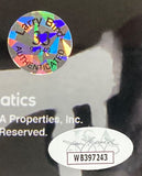 A close-up shows two authentication stickers on the Sports Integrity Larry Bird Signed Framed 16x20 Celtics Photo: a holographic sticker marked "Larry Bird 33 AUTHENTICATED" and a white oval sticker with a signature and code WB397243.