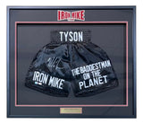 Sports Integrity’s Mike Tyson Signed Framed Custom Black Baddest Man Boxing Trunks (JSA ITP) display features boxing shorts labeled TYSON, IRON MIKE, and THE BADDEST MAN ON THE PLANET, with his signature on the left leg and a gold plaque.