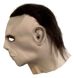 A side view of the Sports Integrity Nick Castle Signed Halloween Michael Myers Rubber Mask The Shape JSA, featuring a pale, expressionless face with hollow eye holes, a prominent ear, and dark messy hair.