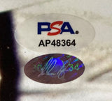 Close-up of two authentication stickers on the Nolan Ryan Signed 16x20 Texas Rangers Ventura Fight Photo by Sports Integrity: a PSA/DNA oval sticker with AP48364 and a holographic oval sticker featuring a faint signature and number 34.