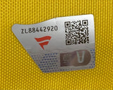 A silver authenticity sticker with code ZL88442920, QR code, red logo, and blue V appears on the textured yellow 144th Open Championship At St. Andrews PGA Event Issued Golf Pin Flag by Sports Integrity.