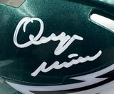 A close-up of a shiny green Quinyon Mitchell Signed Eagles Mini Speed Helmet by Sports Integrity, featuring a white signature and Super Bowl 59 LIX inscription. Part of the helmet's white and black design is visible at the bottom.
