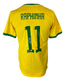 The Sports Integrity Raphina Brazil Signed Yellow Soccer Jersey BAS features green trim, "Raphinha" and number 11 on the back, with the number autographed in black ink. Displayed against a white background.