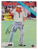 A Ray Floyd Signed Masters Champion 1976 Sports Illustrated Magazine by Sports Integrity features Floyd in a white and red shirt, holding a club on the green, with his large black autograph across his legs.