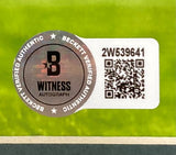 A Saquon Barkley Signed Framed 16x20 Eagles Kelly Green Photo by Sports Integrity includes a Beckett Witness Autograph authentication sticker (serial no. 2W539641) with a QR code and “Beckett Verified Authentic” on a metallic circular label.