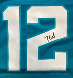 The Sports Integrity Travis Hunter Signed Jacksonville Jaguars Nike Game Replica Jersey features a teal design with a large white number 12 outlined in blue and a black autograph on the number 2.