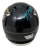 The Trevor Lawrence Signed Jacksonville Jaguars Mini Speed Helmet by Sports Integrity features a black design with team logos, a teal autograph on top, and a visible Fanatics authentication sticker on the back.