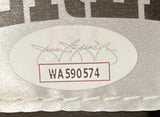 A close-up of a white oval sticker with serial number WA590574, red border, and signature, attached to the fabric of a Mike Tyson Signed Left Black Hand Everlast Boxing Glove Shadowbox by Sports Integrity.