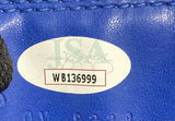 A close-up of a JSA-labeled sticker (code WB136999) on the blue Mike Tyson Signed Left Hand USA Cleto Reyes Boxing Glove from Sports Integrity, with black stitching and part of a black object nearby.