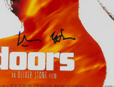Close-up of the Val Kilmer Signed Framed 11x17 The Doors Poster Photo by Sports Integrity, showing white text on a fiery orange background with two black signatures and "AN OLIVER STONE FILM" partially visible below.