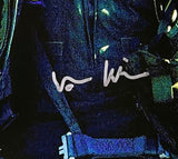 A close-up of a Sports Integrity Val Kilmer Signed 16x20 Top Gun Photo JSA, featuring Val Kilmer’s silver autograph across the center with visible straps and metal details.