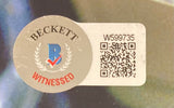 A Larry Wilcox Signed 8x10 CHIPS Sunglasses Photo from Sports Integrity features a Beckett Witnessed sticker with a blue B logo, laurel wreath, red check mark, QR code, and serial number W599735 on a silver and white background.